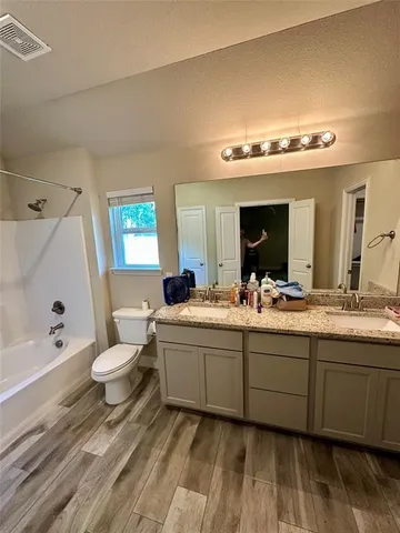 a bathroom with a double vanity sink mirror and toilet