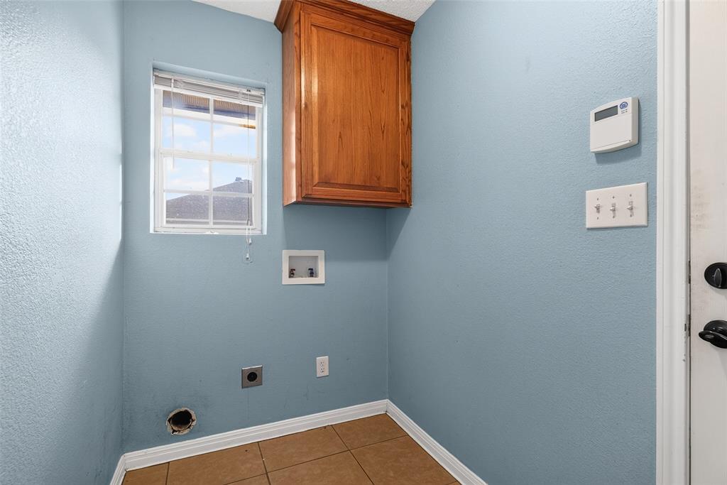 124 Topaz Circle Hewitt, TX 76643 - Photo 12 of 35 Dedicated laundry space featuring a window, overhead cabinetry, tile flooring, and light blue walls