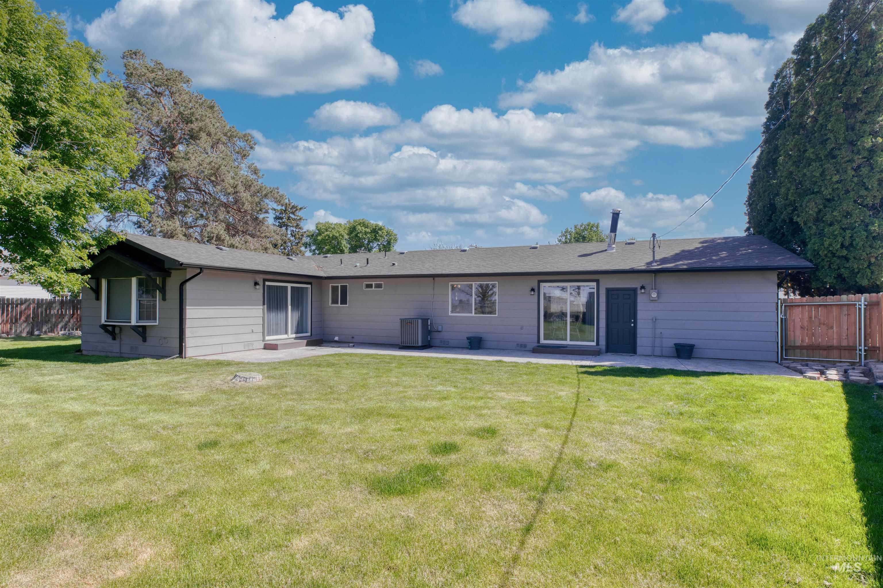 20803 Friends Road Greenleaf, ID 83626 - Photo 22 of 39 Expansive rear lawn featuring a patio area, multiple sliding glass doors, and a bay window