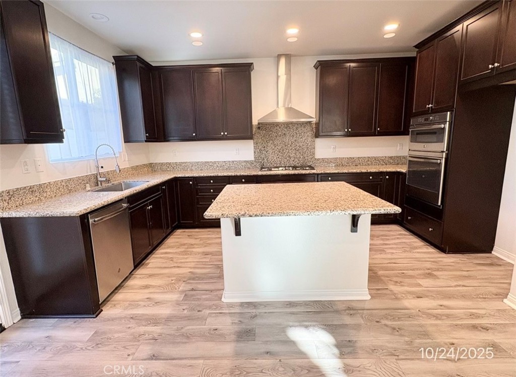 28434 Sunflower Street Highland, CA 92346 - Photo 2 of 22 a kitchen with stainless steel appliances kitchen island granite countertop a stove a sink and a microwave