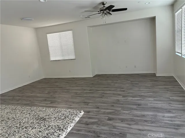 an empty room with wooden floor window and ceiling fan