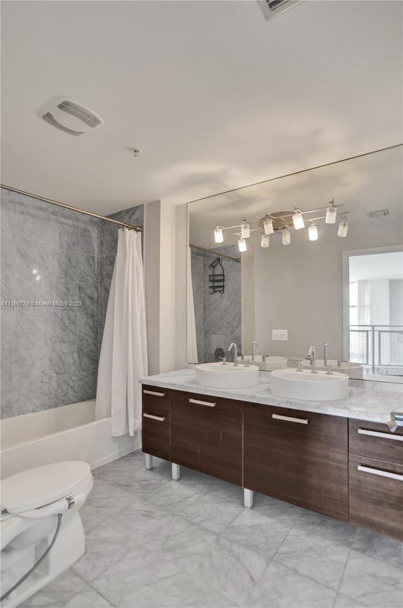 244 Biscayne Boulevard, Unit 439 Miami, FL 33132 - Photo 23 of 49 a bathroom with a double vanity sink and a mirror