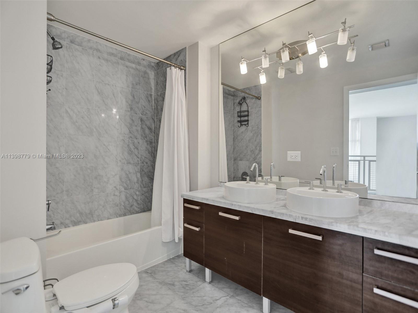 244 Biscayne Boulevard, Unit 439 Miami, FL 33132 - Photo 24 of 49 a bathroom with a granite countertop sink a toilet a mirror a bathtub and shower