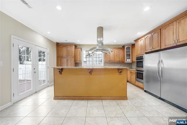 a view of a kitchen with kitchen island a counter top space stainless steel appliances and cabinets
