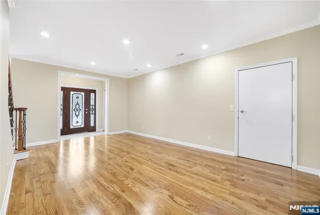 a view of an empty room with window and wooden floor