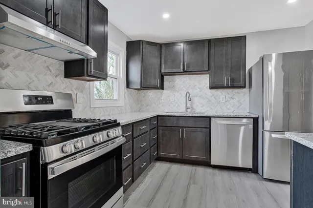 a kitchen with stainless steel appliances granite countertop a stove a sink and a refrigerator