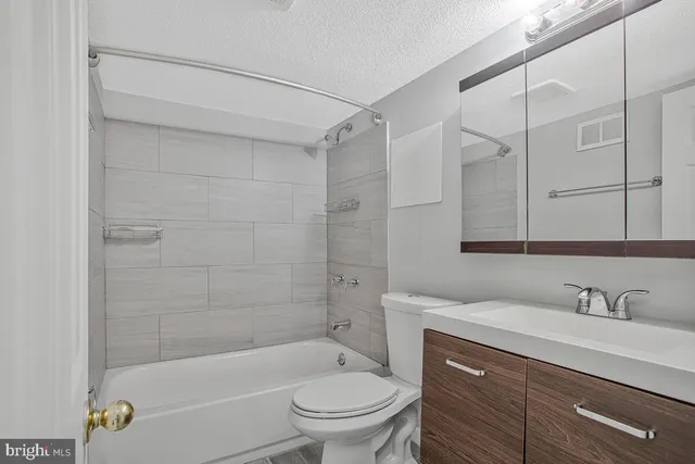 a bathroom with a bathtub shower sink vanity and toilet