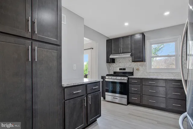 a kitchen with stainless steel appliances granite countertop a refrigerator and a stove top oven