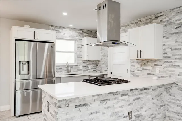 a kitchen with stainless steel appliances granite countertop a refrigerator a sink and white cabinets