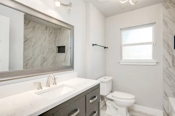 a bathroom with a granite countertop sink toilet and shower