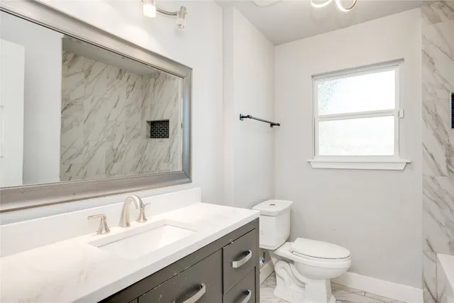 a bathroom with a granite countertop sink toilet and shower