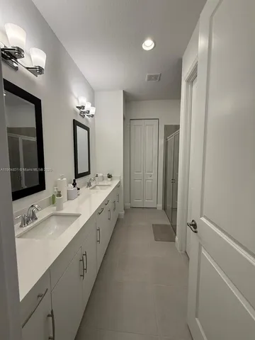 a bathroom with a double vanity sink mirror and shower