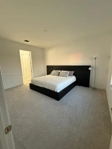a bedroom with a bed and a potted plant on the dresser