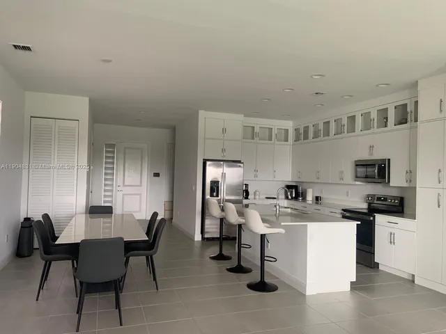 a view of kitchen with cabinets stainless steel appliances and dining table
