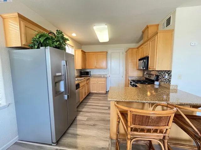 a kitchen with stainless steel appliances granite countertop a refrigerator a stove a sink a washer and dishwasher with wooden cabinets