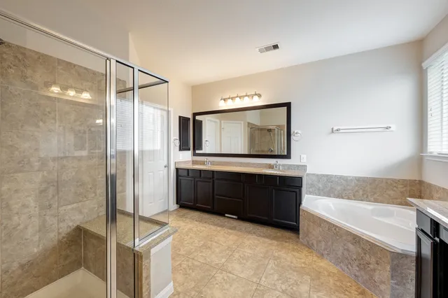 a bathroom with a bathtub mirror and a sink