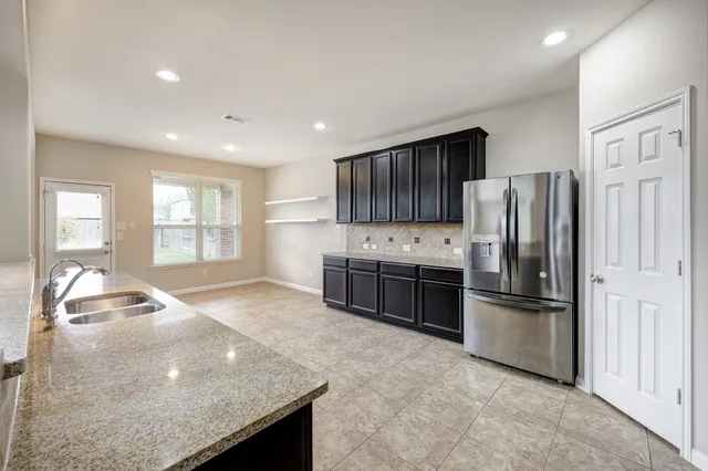 a kitchen with stainless steel appliances granite countertop a refrigerator a stove and a sink with wooden cabinets