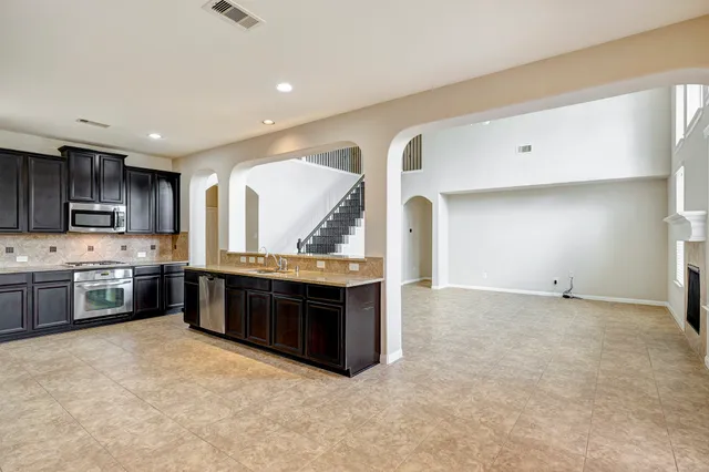 a large kitchen with stainless steel appliances granite countertop a stove a sink and a refrigerator