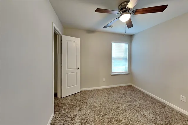 an empty room with closet and a chandelier fan