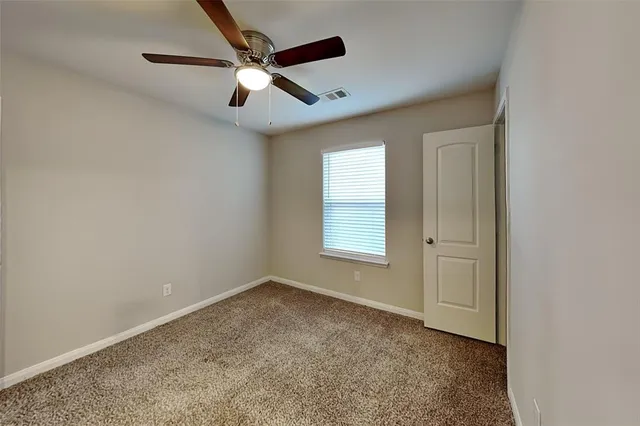 an empty room with ceiling fan and windows