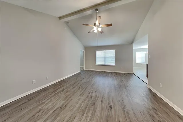an empty room with wooden floor chandelier fan and windows
