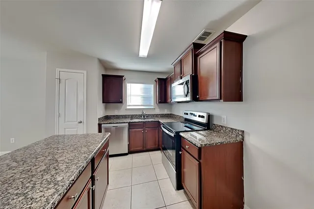 a kitchen with stainless steel appliances granite countertop a stove a sink and a microwave