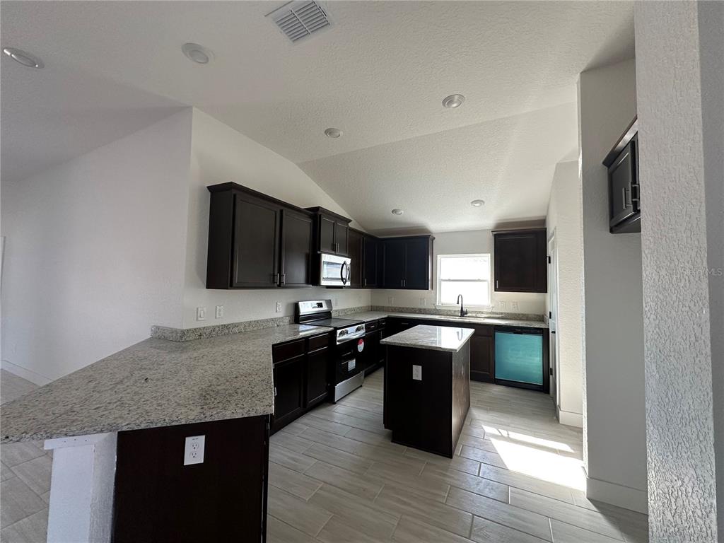 4546 Southwest 90th Ln Road Ocala, FL 34476 - Photo 4 of 9 a kitchen with stainless steel appliances granite countertop a sink stove and refrigerator
