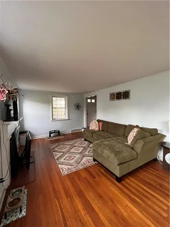 a living room with couches and dresser with wooden floor