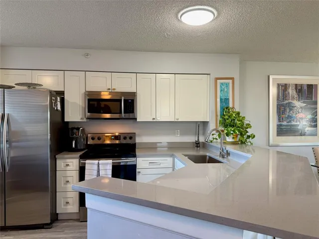 a kitchen with stainless steel appliances granite countertop a refrigerator a stove and a sink