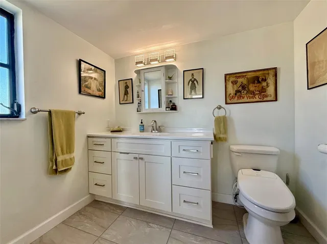 a bathroom with a granite countertop toilet sink and mirror