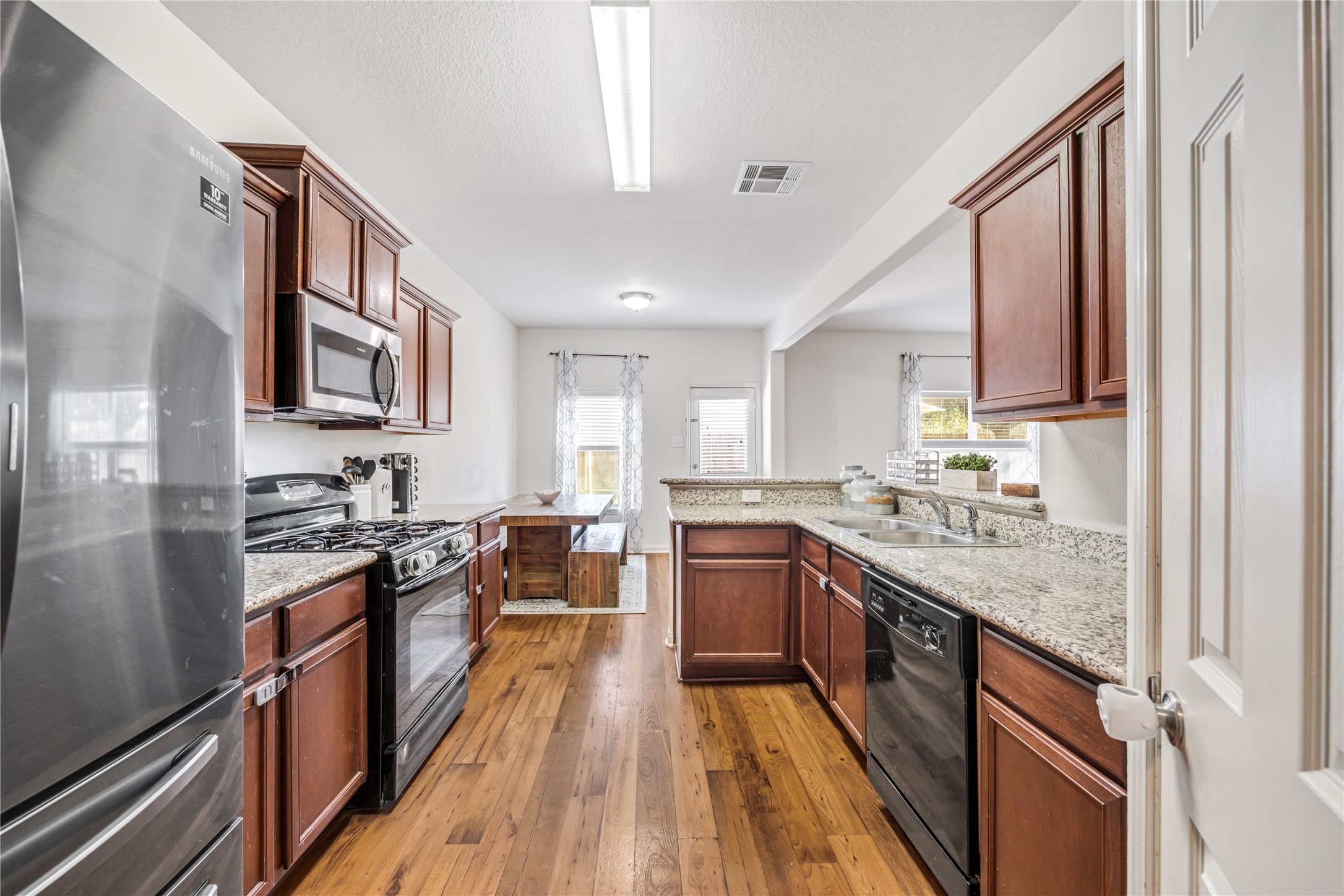 319 Falling Pine Drive Conroe, TX 77304 - Photo 8 of 22 a kitchen with stainless steel appliances granite countertop hardwood floor sink stove and wooden cabinets