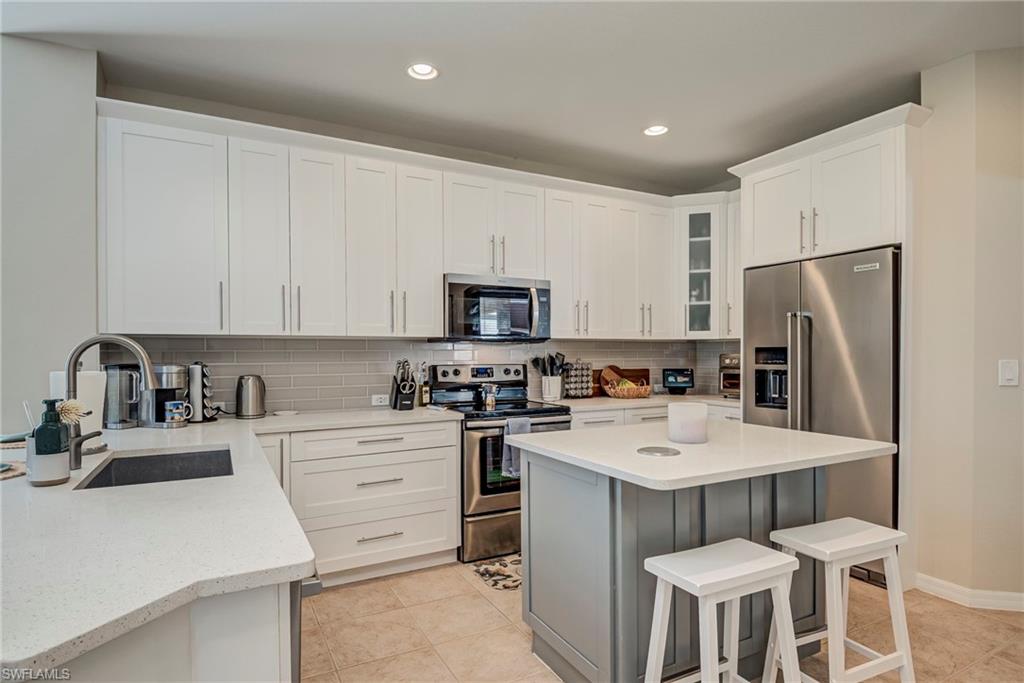 1897 Par Drive Naples, FL 34120 - Photo 10 of 31 a kitchen with a sink a stove a refrigerator and white cabinets