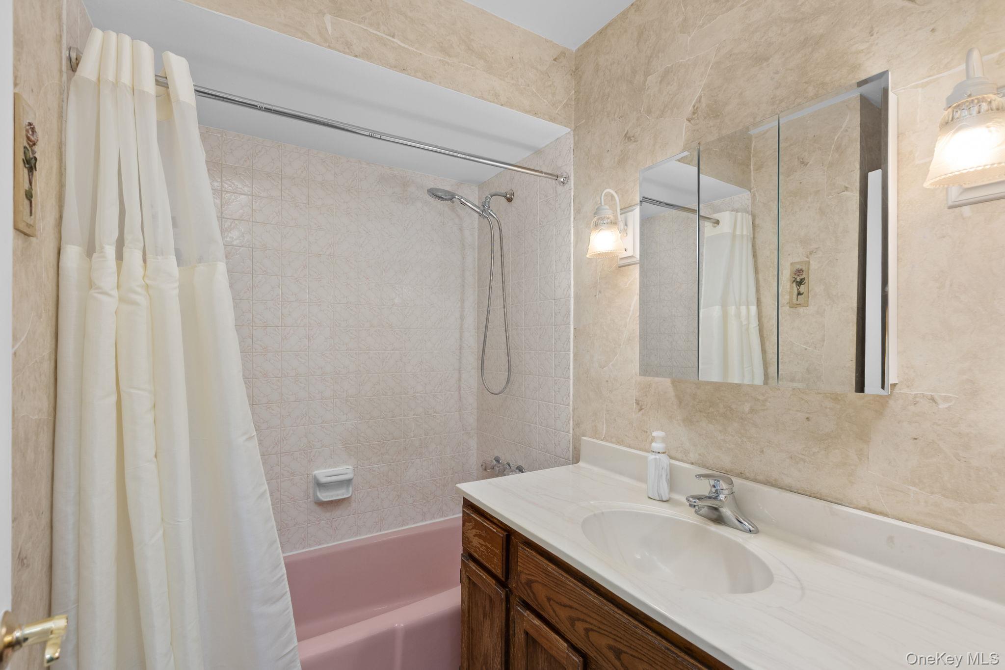 25 Harmony Road Brewster, NY 10509 - Photo 19 of 42 Bathroom with pink soaking tub, tri-view medicine cabinet and wood vanity.