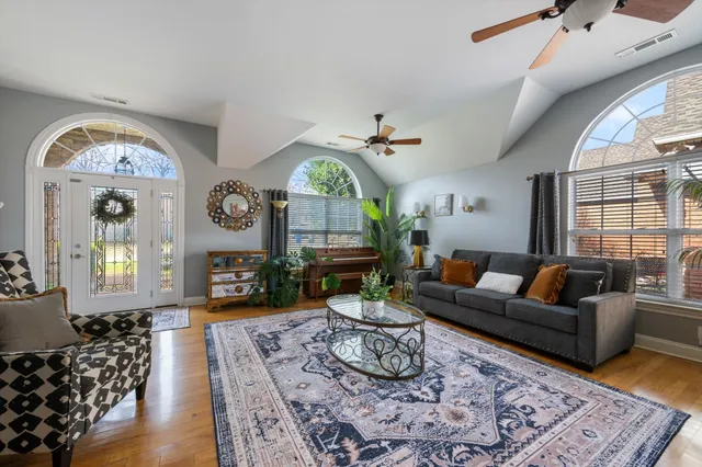 a living room with furniture a large window and wooden floor