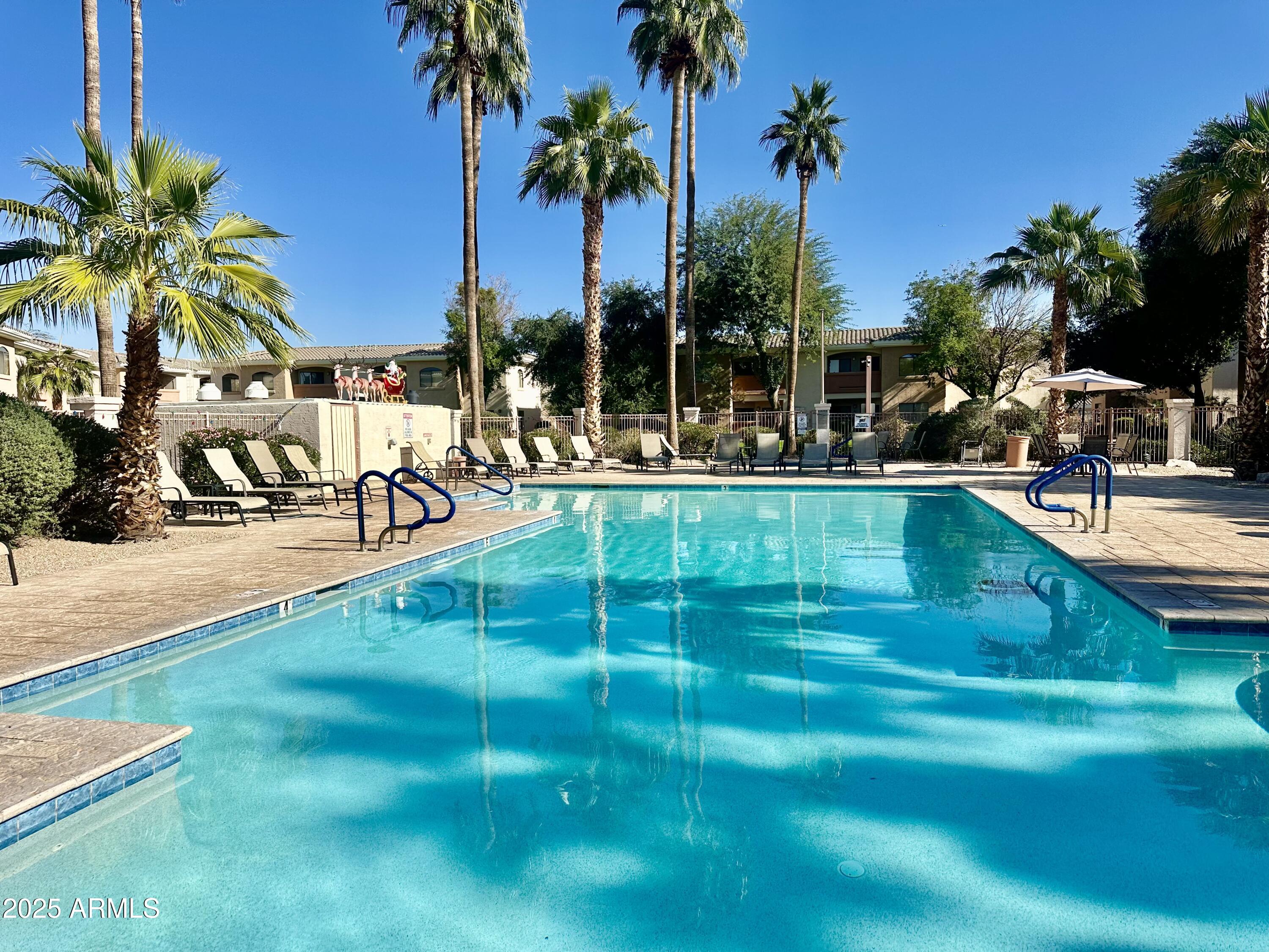 10030 West Indian School Road, Unit 227 Phoenix, AZ 85037 - Photo 5 of 22 a view of a swimming pool with a table and chairs