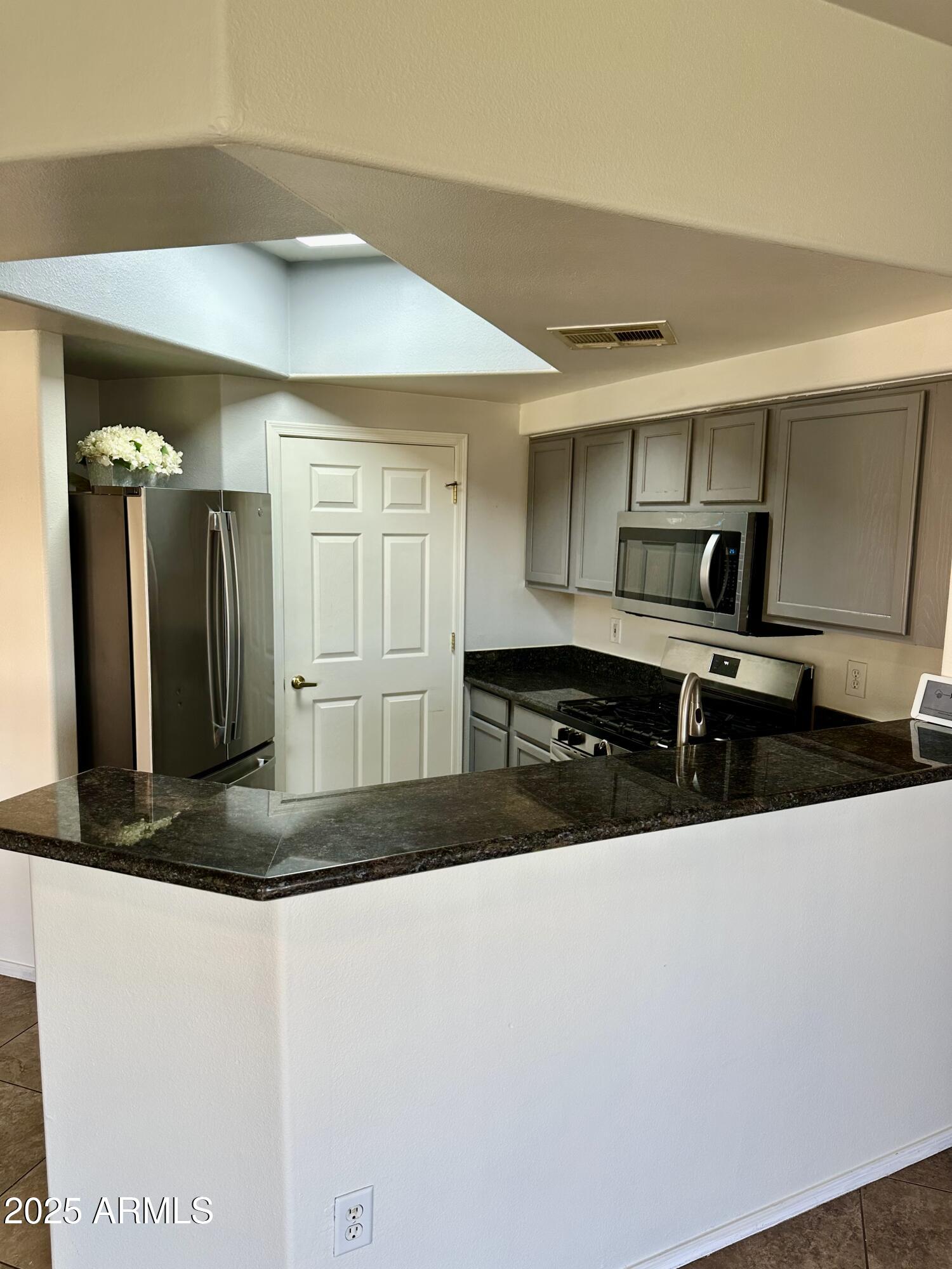 10030 West Indian School Road, Unit 227 Phoenix, AZ 85037 - Photo 9 of 22 a kitchen with stainless steel appliances granite countertop a sink a stove and a refrigerator