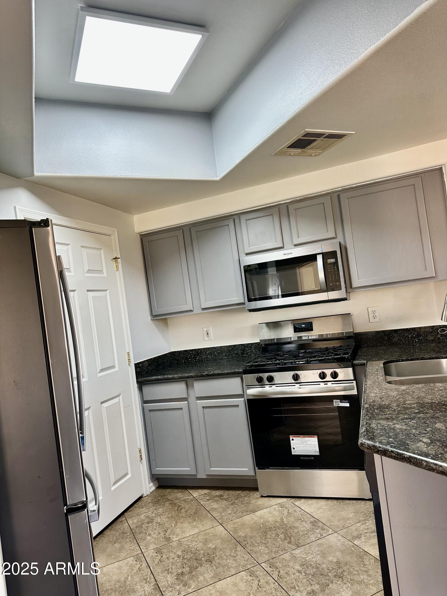 10030 West Indian School Road, Unit 227 Phoenix, AZ 85037 - Photo 10 of 22 a kitchen with stainless steel appliances granite countertop a stove and a refrigerator
