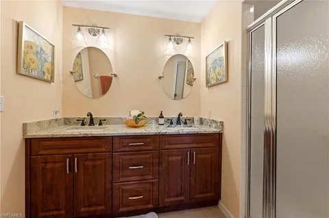 a bathroom with a granite countertop double vanity sink and a mirror