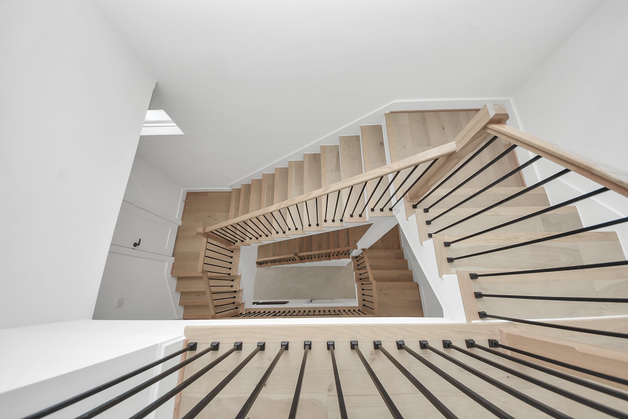 927 Fisher Street, Unit B Houston, TX 77018 - Photo 19 of 47 Ascend through this striking architectural moment, where a sculptural staircase becomes a design statement in itself. Warm wood treads contrast beautifully against crisp white walls, while sleek black railings guide your eye upward through the home’s airy vertical space. Bathed in natural light from above, this staircase creates an elegant transition between levels, blending modern design with a sense of openness and flow.