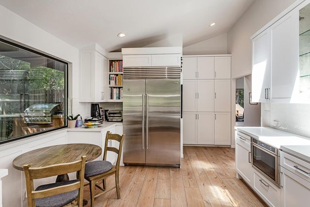 a kitchen with a refrigerator a stove and white cabinets with wooden floor