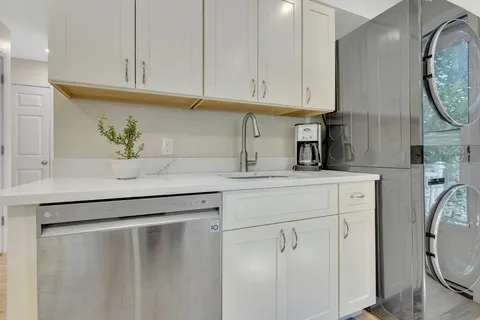 a kitchen with white cabinets and clock on the wall