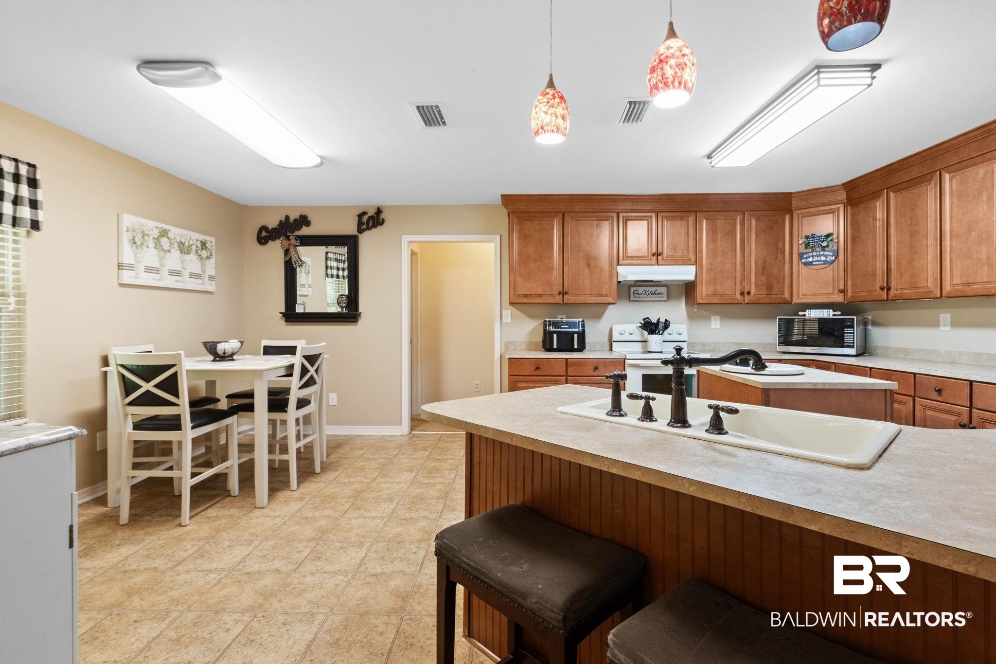16151 Tolbert Road Bay Minette, AL 36507 - Photo 10 of 74 Kitchen featuring wood-finish cabinetry, a central island with an integrated sink and breakfast bar, and tile flooring