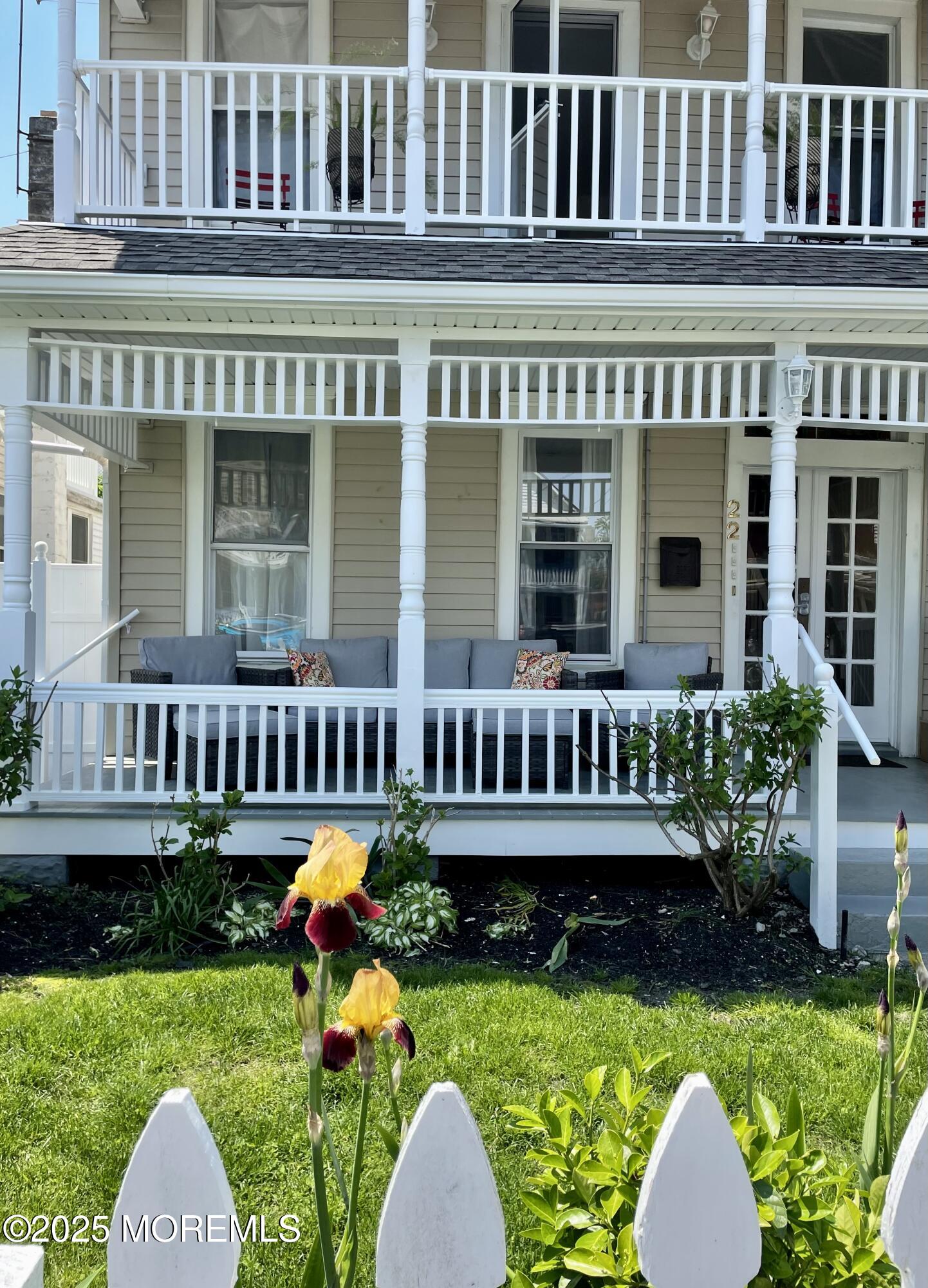 front view of a house with a yard and a table and chairs under an umbrella