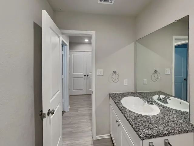 a bathroom with a granite countertop double vanity sink mirror and shower