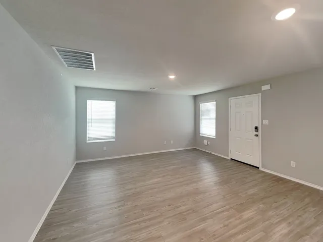 an empty room with wooden floor and windows