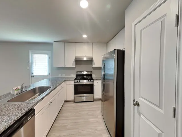 a kitchen with stainless steel appliances granite countertop a refrigerator and a sink
