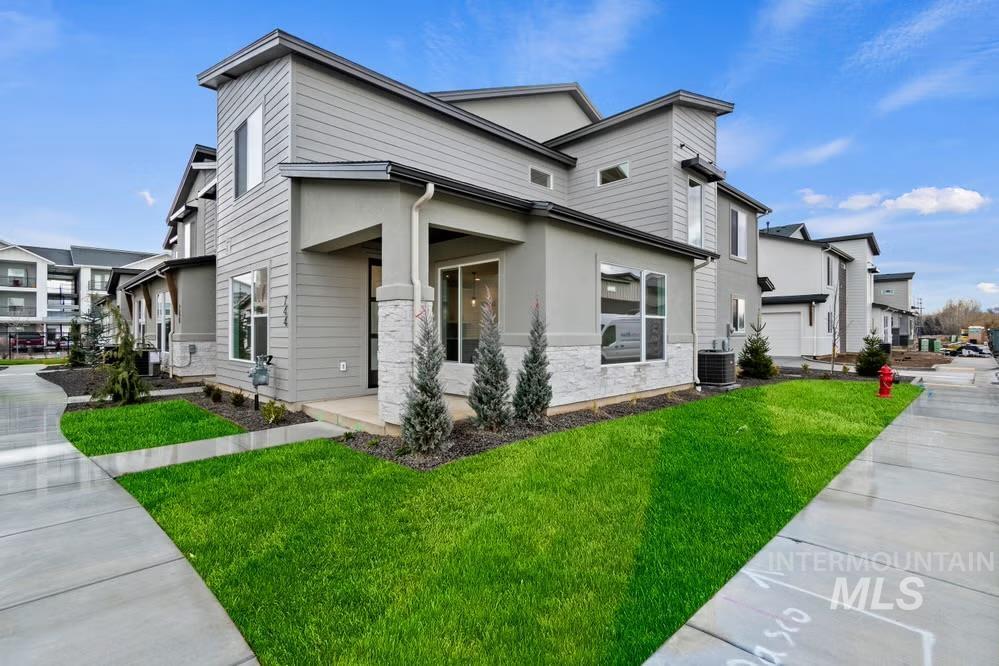 744 South Calhoun Lane Star, ID 83669 - Photo 2 of 34 Contemporary house featuring a front yard, stucco siding, and stone siding