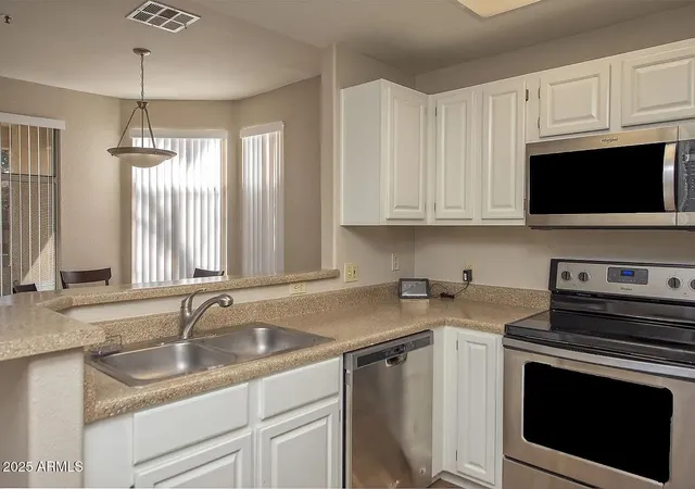 a kitchen with stainless steel appliances granite countertop a sink dishwasher a stove and a microwave oven with cabinets