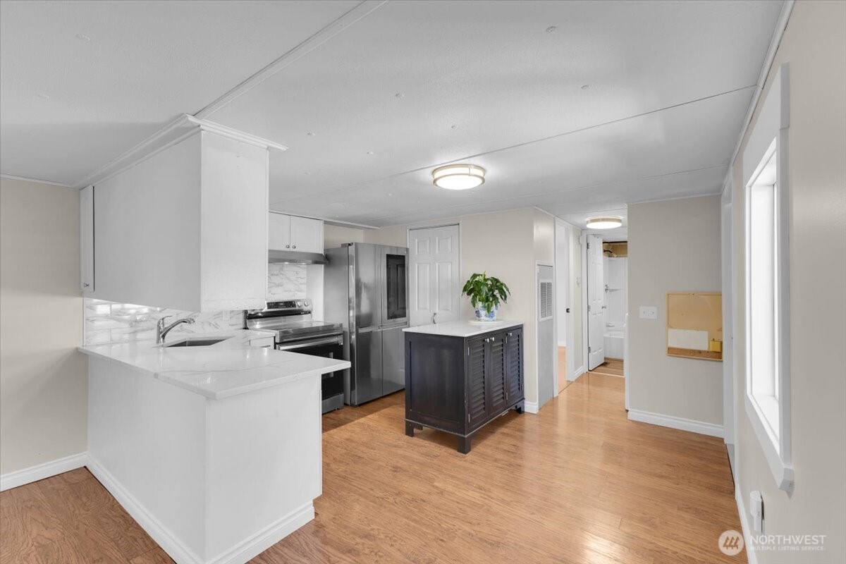 7614 Northeast Bothell Way, Unit 11 Kenmore, WA 98028 - Photo 11 of 26 a view of a kitchen with kitchen island a sink wooden floor and living room view