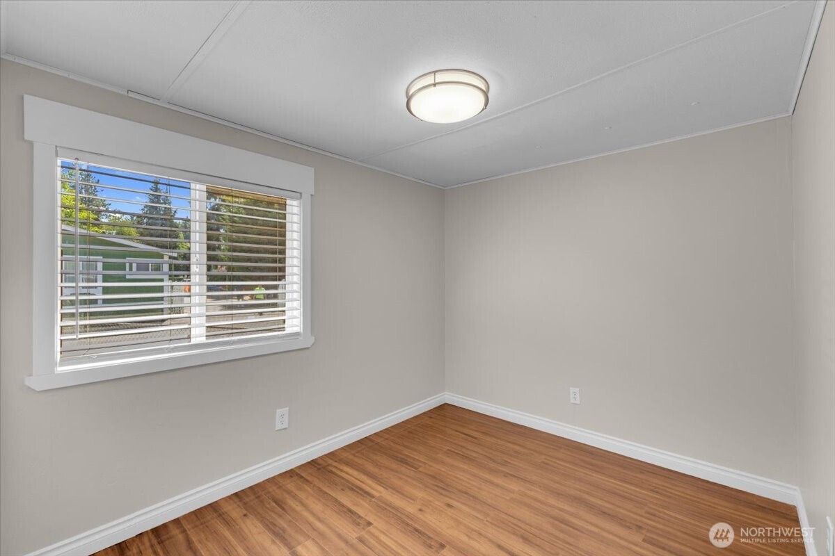 7614 Northeast Bothell Way, Unit 11 Kenmore, WA 98028 - Photo 19 of 26 a view of an empty room with wooden floor and a window